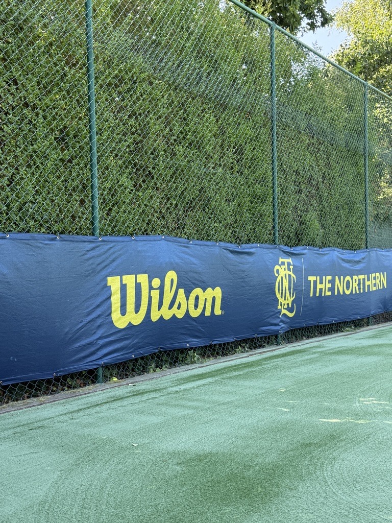 Navy tennis windbreak fitted to court fencing